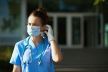 medicinska sestra ispred bolnice drži zaštitnu masku na licu