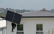 Radnik nosi solarni panel koji treba da postavi na krov kuće