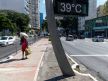 Žena se štiti od vrućine u Brazilu dok je na ekranu ispisano da je temperatura 39 stepeni