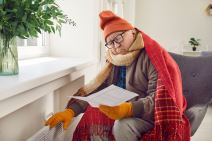 muškarac umotan u ćebe sedi pored radijatora