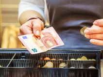 Kasirka u ruci drži novčanicu od 10 evra