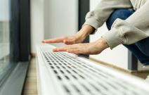 žena greje ruke na radijatoru