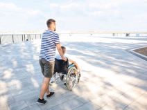 Otac koji gura sina u invalidskim kolicima