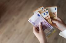 žena drži evre u ruci i novčanicu od 500 evra koja više neće biti u upotrebi