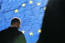 čovek stoji ispred zastave evropske unije