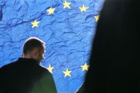 čovek stoji ispred zastave evropske unije