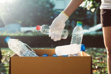 Žena stavlja plastične flaše u kutiju tokom čišćenja parka