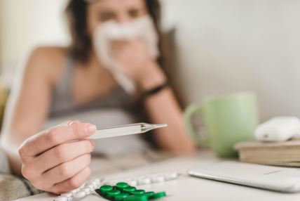 žena meri temperaturu dok joj curi nos zbog prehlade