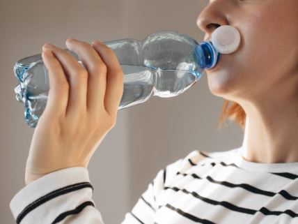 Žena pije vodu iz plastične flaše