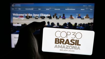 čovek drži mobilni telefon na kome piše logo klimatskog samita COP30 koji će se održati u Belemu u Brazilu