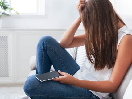 Zabrinuta devojčica drži telefon