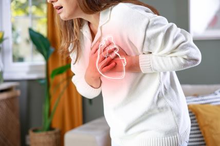 Devojka u belom džemperu se drži za grudi - oseća bol i gušenje