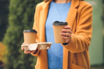 žena drži dve kafe za poneti u kartonskim ambalažama