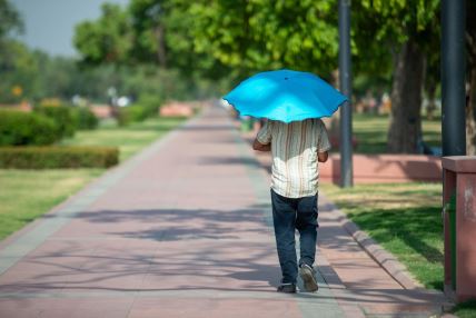 čovek šeta sa kišobranom koji ga štiti od vrućine usled snažnog toplotnog talasa u Indiji