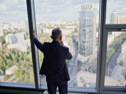 Biznismen posmatra grad iz kancelarije