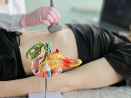 žena u crnoj majci leži na leđima na stolu u ordinaciji na ultrazvučnom pregledu pankreasa