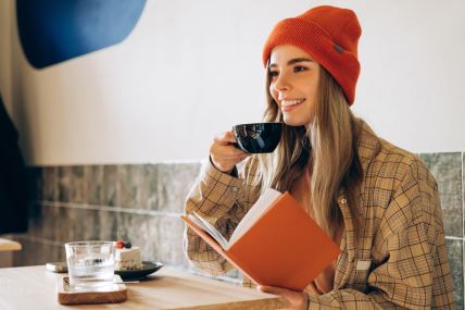devojka pije kafu i čita knjigu u kafiću