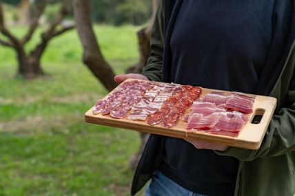 muškarac drži dasku za meze sa različitim vrstama suvog mesa