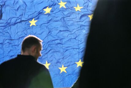 čovek stoji ispred zastave evropske unije