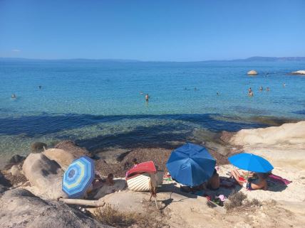 Turisti sede pod suncobranima na plaži na Sitoniji u Grčkoj