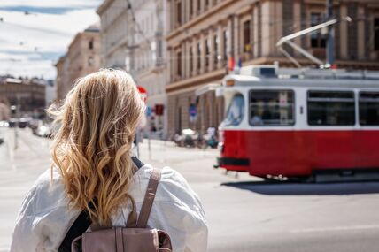 žena čeka da prođe tramvaj na ulici u Beču