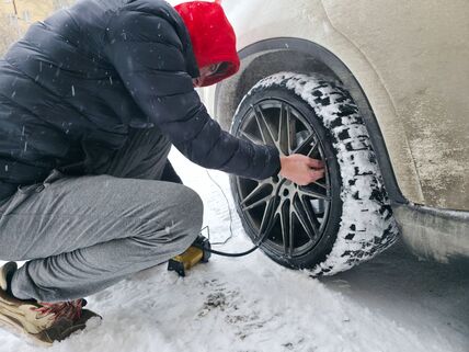 muškarac pumpa gumu na automobilu