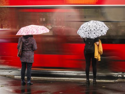Žene sa kišobranima čekaju da pređu ulicu u Beogradu