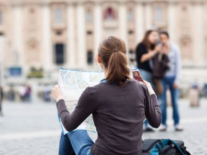 Mlada turistkinja proučava mapu na trgu Svetog Petra u Vatikanu u Rimu.