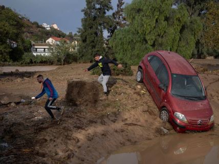 Muškarci trče pored automobila zaglavljenog u blatu u poplavama u Malagi