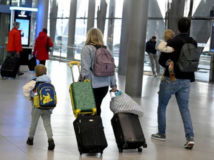 Roditelji sa dvoje dece vuku kofere na aerodromu