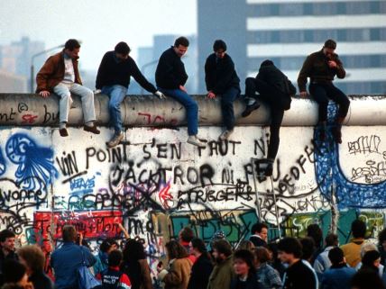 Ljudi sede na Berlinskom zidu u novembru 1989. nakon što je srušen