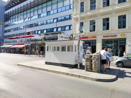 Turisti poziraju pored stražarske kućice Čekpoint Čarlija u Berlinu dok se u pozadini nalazi restoran Mekdonalds