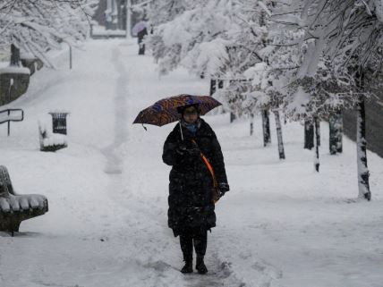 Žena sa kišobranom prolazi kroz Sarajevo koje je prekriveno snegom