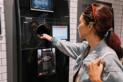 Žena ubacuje plastične flaše u automat za reciklažu