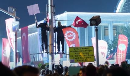 Dva muškarca stoje na banderi tokom protesta u Turskoj