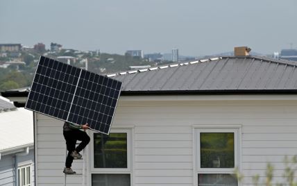 Radnik nosi solarni panel koji treba da postavi na krov kuće