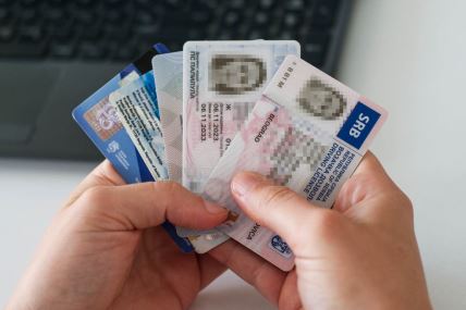 osoba drži u ruci lična dokumenta, vozačku dozvolu, ličnu kartu...