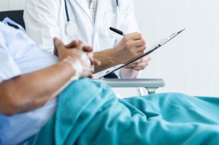 pacijent koji leži u bolničkom krevetu razgovara sa doktorom