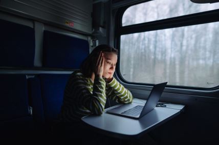 žena sedi u vozu i gleda u laptop