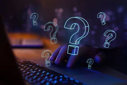 znakovi pitanja iznad tastature kompjutera koji ilustruju traženje informacija na internetu