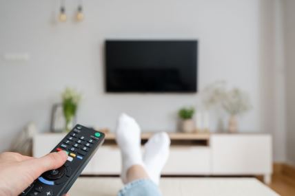 Devojka drži daljinski kako bi upalila televizor