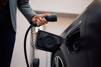 Muškarac drži punjač električnog automobila