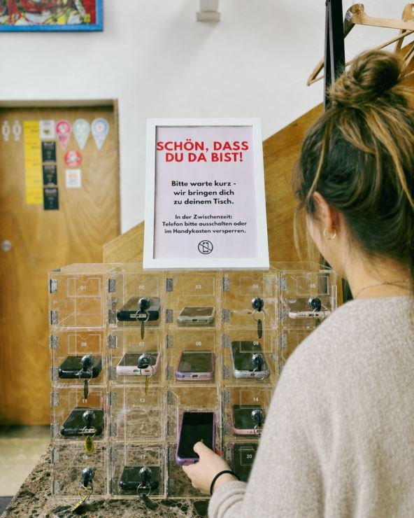 devojka ostavlja telefon na ulazu u kafić za digitalni detoks