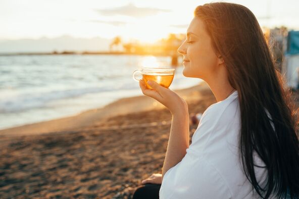 žena na plaži pije čaj