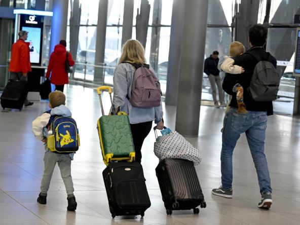 Roditelji sa dvoje dece vuku kofere na aerodromu