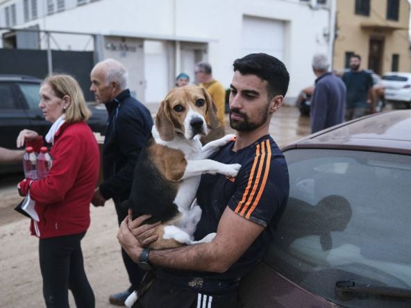 Muškarac drži psa u naručju nakon razornih poplava u Valensiji