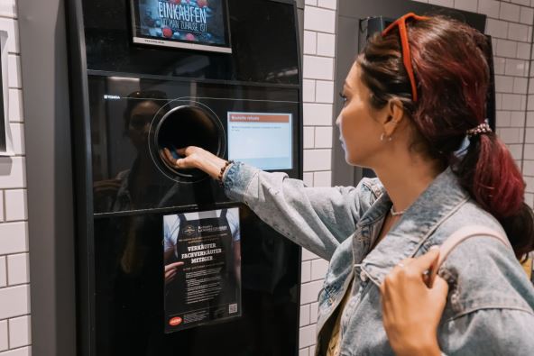 Žena ubacuje plastične flaše u automat za reciklažu